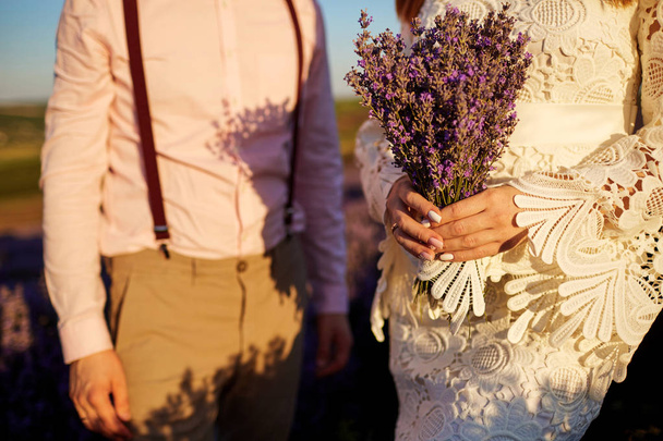 Close-up of a bouquet of lavender in the hands of the bride and groom. - Fotoğraf, Görsel