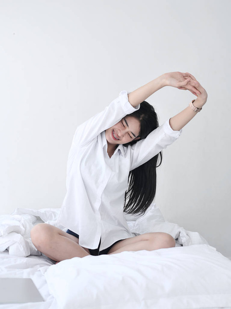 Attractive Asian girl sitting on white bed and relax at home. - Foto, immagini