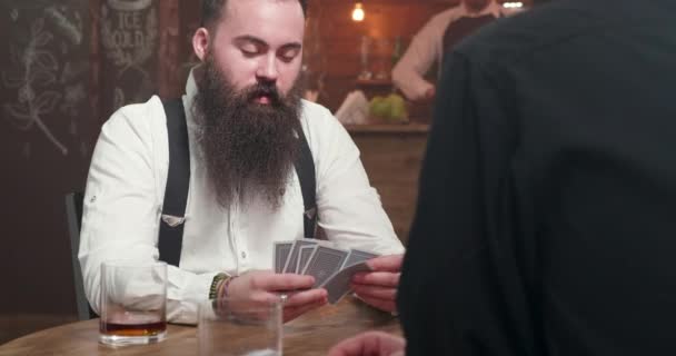 Man met lange baard glimlachend en speelkaarten met een vriend - Video