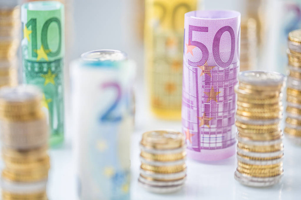 Rolled euro banknotes and coins towers stacked in other position - 写真・画像