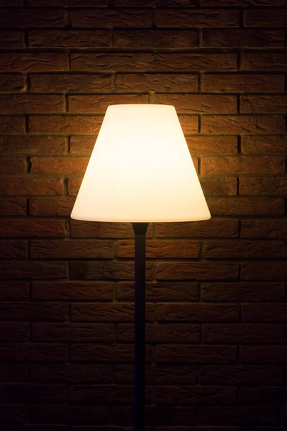 Old vintage evening lamp shines bright light to dark wall - Photo, Image