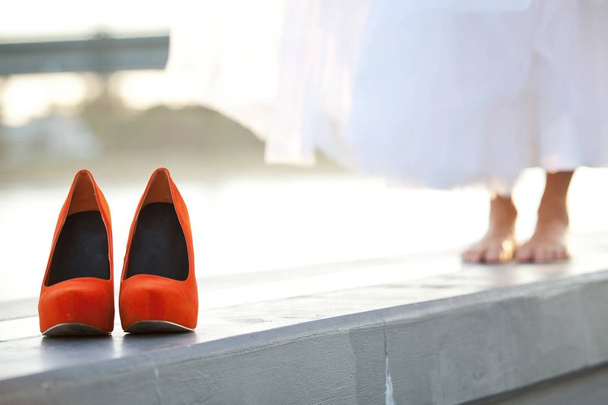 Red-orange wedding shoes in front of barefoot bride - Zdjęcie, obraz