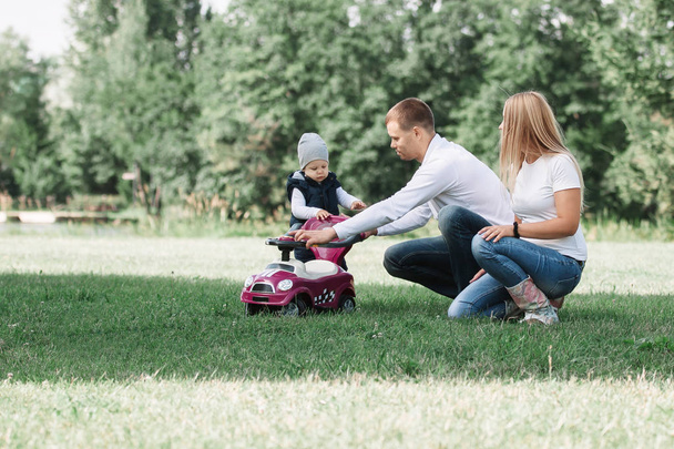 parents play with their little son on the lawn in the Park. - 写真・画像