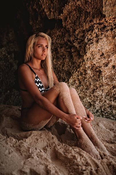 beautiful woman with long blonde hair in dark swimwear posing on - Foto, Imagem