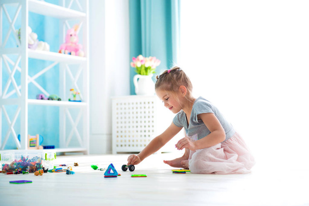 Little girl child playing with toys on warm floor indoors - Foto, Bild