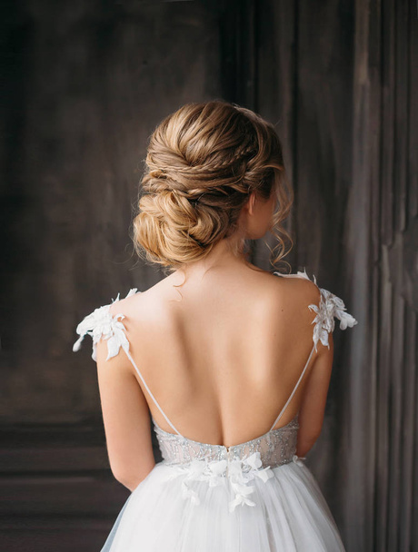 gorgeous professional hairstyle for blond long hair, advertising announcement of beauty salon for wedding and prom 2019, image of graduate in white expensive adorable dress with open back - Foto, Bild