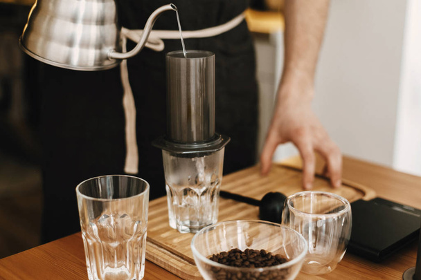 Professional barista in black stylish apron pouring hot water in - Foto, imagen