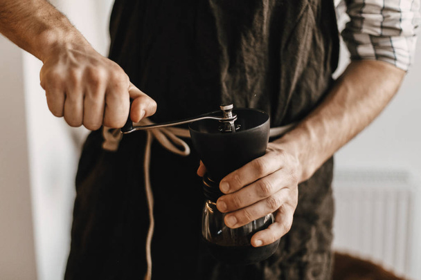 Professionele barista in zwarte stijlvolle schort koffie voor slijpen  - Foto, afbeelding