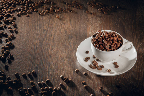A white cup filled with natural roasted coffee beans. - Фото, зображення