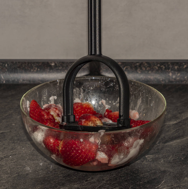 Herstellung von Erdbeeren mit Zucker auf schwarzem Tisch in weißer Küche - Foto, Bild