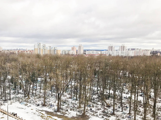 Eski şehir mezarlık ağaçlarıyla bir yükseklikten parkta ve evleri kışın penceresinden görünümü. Şehir Panoraması - Fotoğraf, Görsel