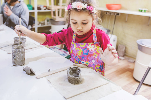 Petite fille à l'atelier de poterie travaillant avec de l'argile
 - Photo, image