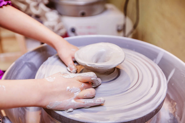 young potter hands working with clay on pottery wheel - Фото, зображення