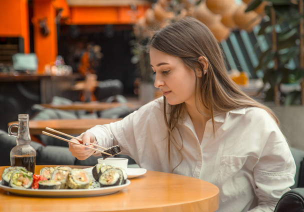 Mujer joven comiendo y disfrutando de sushi fresco
 - Foto, Imagen