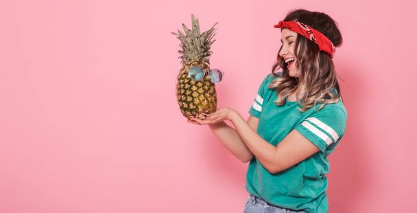 Porträt eines Mädchens mit Ananas auf rosa Hintergrund - Foto, Bild