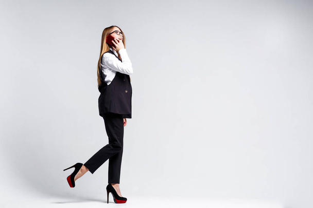 Businesswoman walking and talking on smartphone isolated on white background - Photo, Image