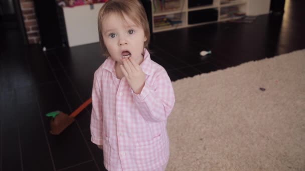 Child standing on floor and curiously looking at camera. - Footage, Video