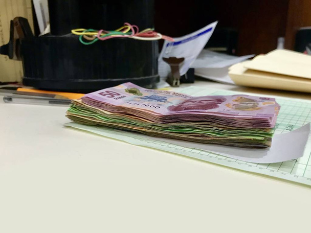 Many mixed Mexican peso bills spread over a beige desk - Photo, Image