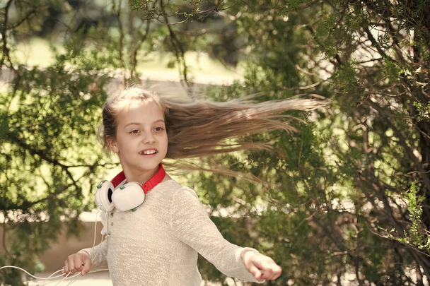 Child dancer with long flying hair. Kid dance to music in summer park. Small girl enjoy music in headphones outdoor. Melody sound and mp3. Summer fun and joy - Fotografie, Obrázek
