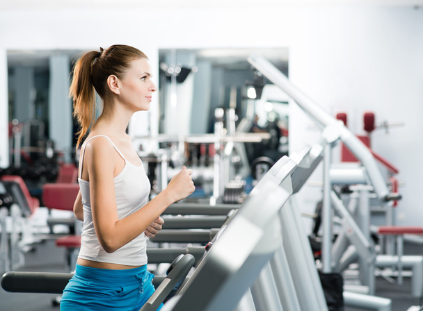 attractive young woman runs on a treadmill - Foto, afbeelding