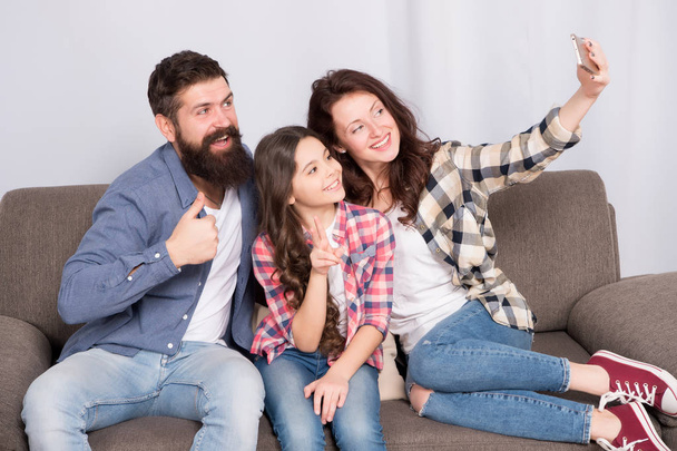 Selfie. Happy family at home. Modern smartphone. Little girl use smartphone with mother and father. bearded man and woman with child. Selfie mania. Family make selfie on smartphone. I love selfie - Foto, Imagen