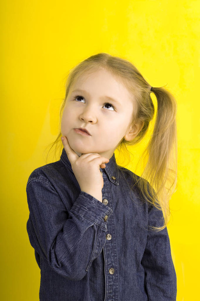 little girl thinks. emotions. on yellow background - Photo, Image