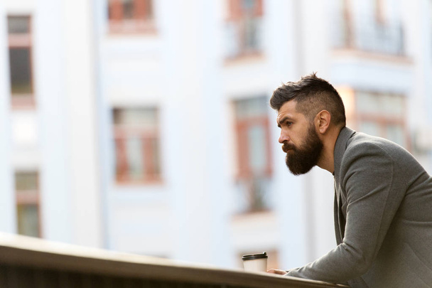 A tasty way to start his day. Businessman in hipster style holding takeaway coffee. The best time of day to drink coffee. Hipster with paper cup walking in city. Bearded man enjoying morning coffee - Foto, imagen