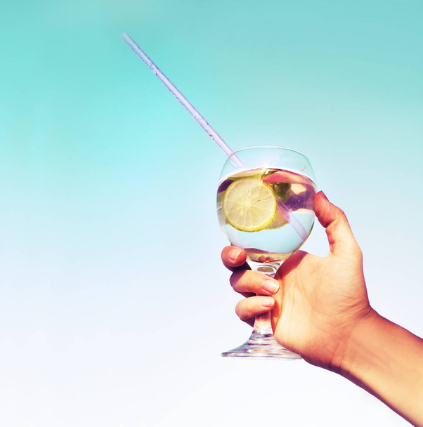 Person hand holding glass of refreshing cocktail, summer vacation background - Photo, Image