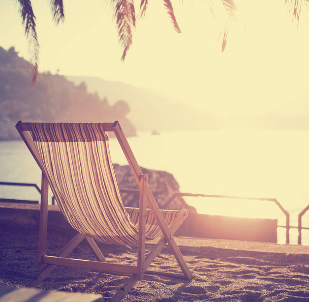 Summer vacation background with beach chair on resort coast at sunset - Fotoğraf, Görsel