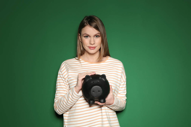 Young woman with piggy bank on color background - Photo, Image