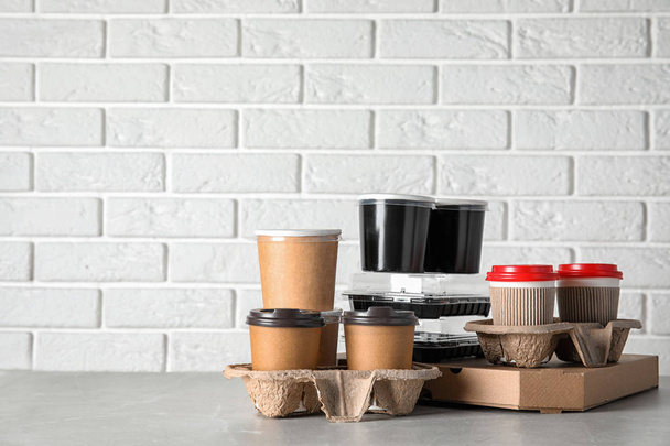 Various takeout containers on table against white brick wall, space for text. Food delivery service - Fotoğraf, Görsel
