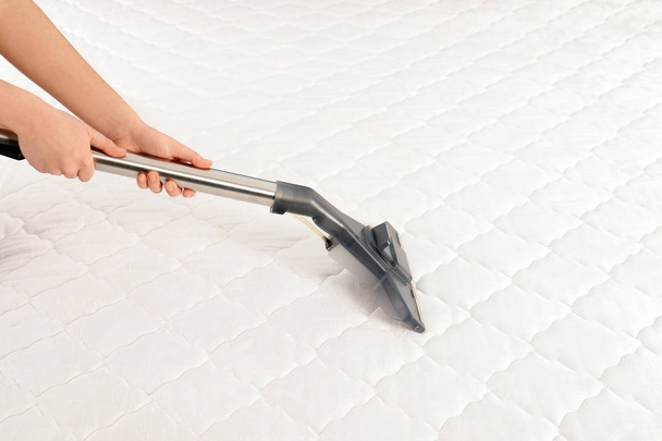 Woman disinfecting mattress with vacuum cleaner, closeup. Space for text - Foto, afbeelding