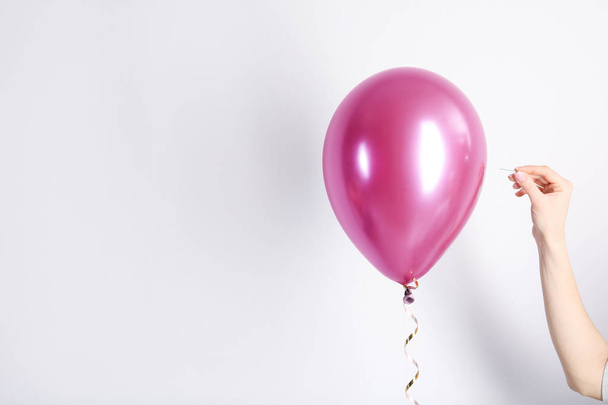 Woman piercing balloon with needle on white background, closeup - Photo, Image