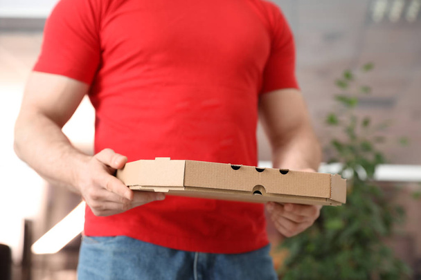 Courier with pizza box on blurred background, closeup - Φωτογραφία, εικόνα