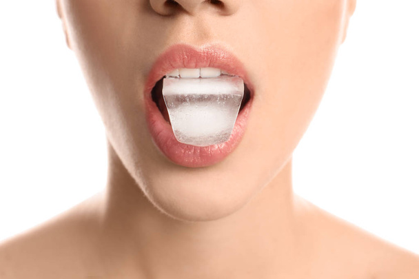 Young woman holding ice cube in mouth on white background, closeup - Фото, зображення
