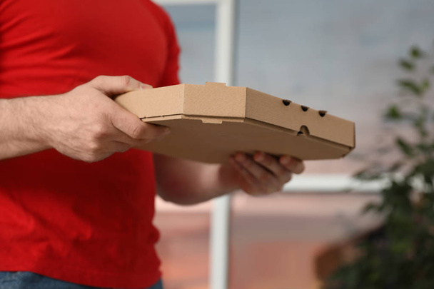 Courier with pizza box on blurred background, closeup - Valokuva, kuva