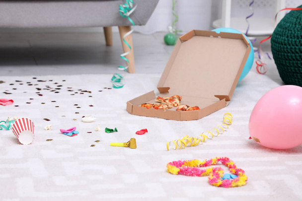 Pizza box with leftovers on messy apartment floor. After party chaos - Фото, изображение
