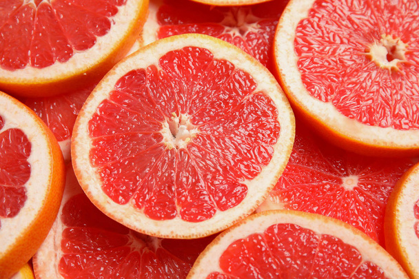 Many sliced fresh ripe grapefruits as background, closeup - Foto, afbeelding
