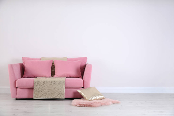 Stylish pink sofa against white wall in modern living room interior. Space for text - Фото, изображение