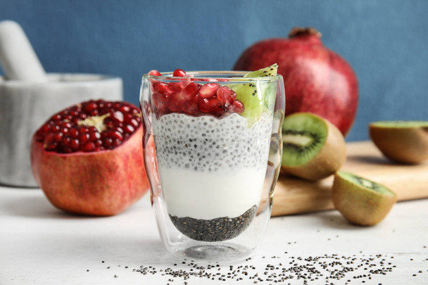 Glass of tasty chia seed pudding with kiwi and pomegranate on table - Foto, afbeelding