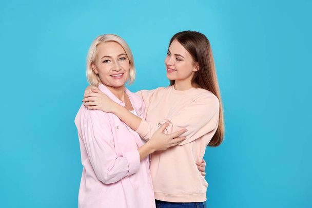 Portrait of mature woman and her daughter on color background - Fotografie, Obrázek
