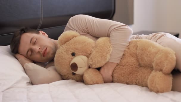 Guy is sleeping with teddy bear - Filmati, video