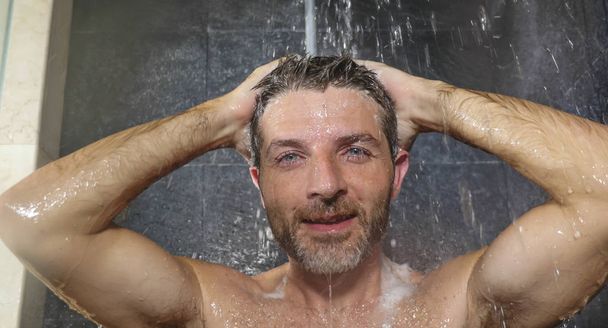 natural face portrait of young attractive and happy man at home or gym bathroom enjoying morning shower washing his hair with shampoo relaxed and cheerful - Photo, Image