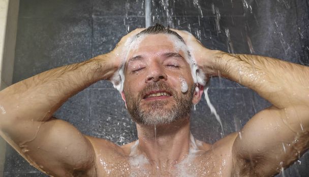 natural face portrait of young attractive and happy man at home or gym bathroom enjoying morning shower washing his hair with shampoo relaxed and cheerful - Foto, Bild