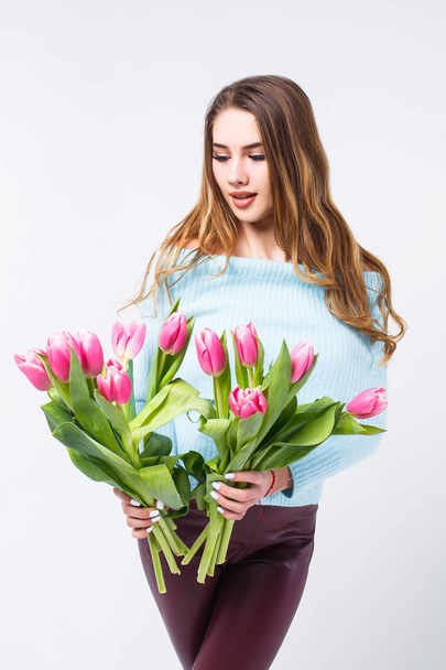 attraktive junge Frau im blauen Pullover mit einem Strauß Tulpen auf weißem Hintergrund - Foto, Bild
