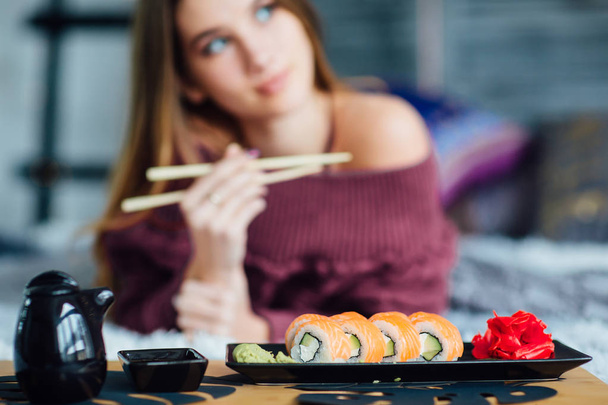 Focus at sushi on black plate, blurred young woman at background - Foto, imagen