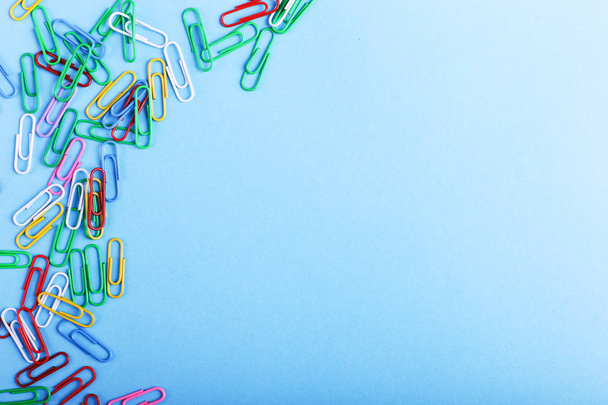Multicolored paper clips on a blue background, pattern, copy space. - Photo, Image