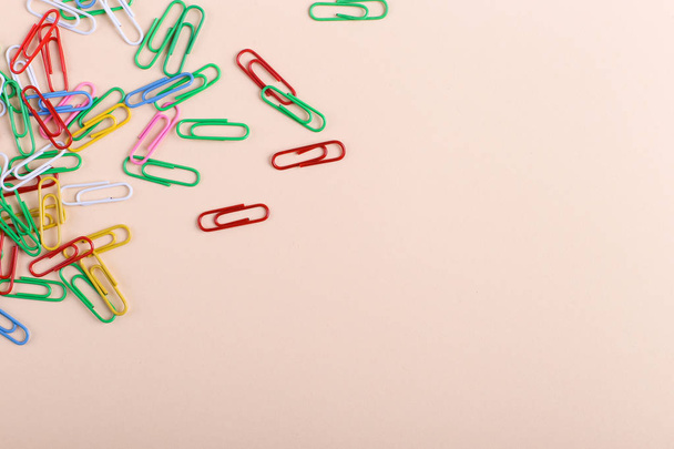 Multicolored paper clips on a coral background, pattern, copy space. - 写真・画像