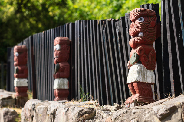Tradycyjny Carvings Maori, Nowa Zelandia. Rząd małych ludzkich figur wzdłuż ogrodzenia, każdy reprezentujący wojownik niosący zwykły lub Greenstone klubu  - Zdjęcie, obraz