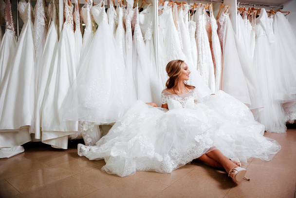 魅力的な若い花嫁はウェディング ドレスを選択しながら笑っています。 - 写真・画像